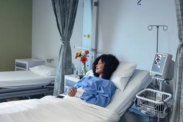アフリカ系アメリカ人の女性患者が寝たきりの病院のベッドに横になって笑っている 医療サービス — ストック写真