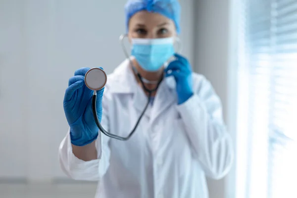 顔のマスクをした白人女性医師がカメラに聴診器を持っている コロナウイルスにおける医療 医療サービス Covid 19パンデミック — ストック写真