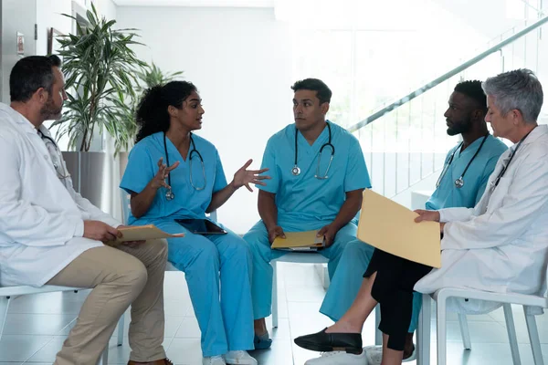 不同的男医生和女医生坐在医院走廊里讨论 保健和保健服务 — 图库照片