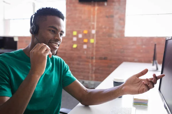 非裔美国商人坐在电脑前 用耳机进行视频通话 独立创意设计业务 — 图库照片
