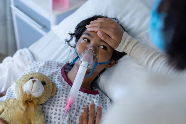 Mãe Raça Mista Máscara Facial Tocando Testa Filha Doente Ventilador — Fotografia de Stock