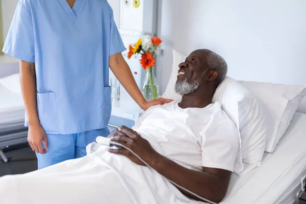 アフリカ系アメリカ人男性が病院の患者室で人種混合女性医師に笑顔 医療サービス — ストック写真