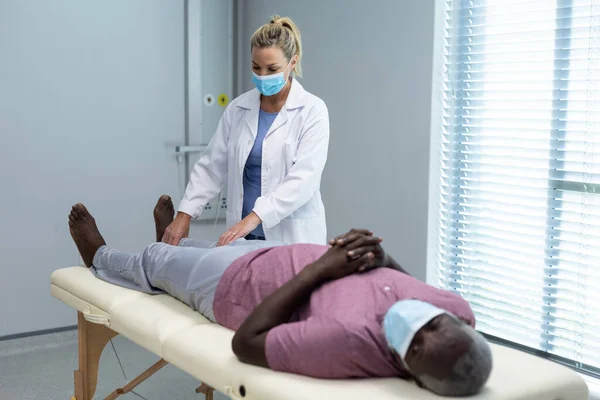 Physiothérapeute Caucasienne Portant Masque Étirant Jambe Patient Afro Américain Médicaments — Photo