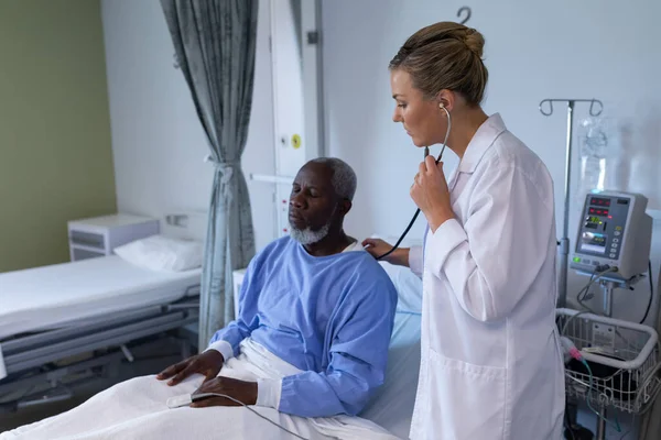 白种人女医生检查与听诊器非洲裔美国男性病人在医院房间 保健和保健服务 — 图库照片