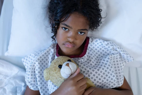 Портрет Хворої Змішаної Дівчини Лежить Лікарняному Ліжку Тримає Плюшевого Ведмедя — стокове фото