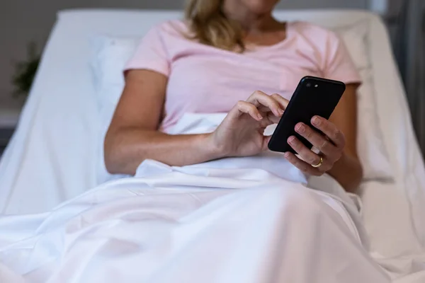 高加索女性患者的中段使用智能手机躺在病床上 保健和保健服务 — 图库照片