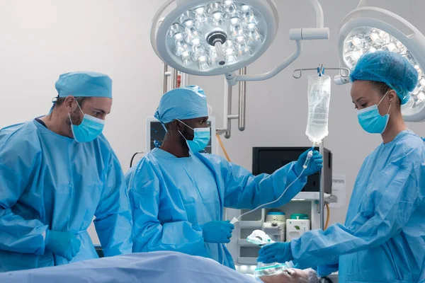 手術室で顔のマスクと外科手術の全体を身に着けている多様な男性と女性の医師 コロナウイルスにおける医療 医療サービス Covid 19パンデミック — ストック写真