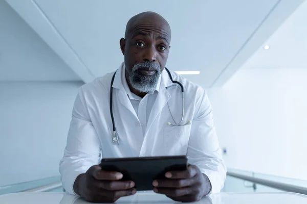 Médico Masculino Afroamericano Sosteniendo Tableta Sentada Escritorio Dando Consulta Videollamada —  Fotos de Stock