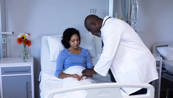 非洲裔美国男医生在床上用脉冲血氧计对混血女病人的手指进行治疗 保健和保健服务 — 图库照片