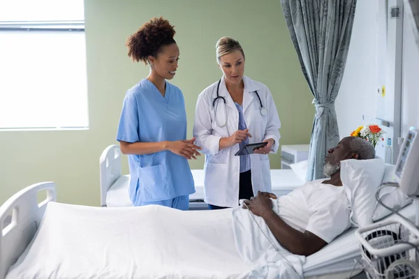 2人の多様な女性医師とアフリカ系アメリカ人男性患者が病室で話をしている 医療サービス — ストック写真