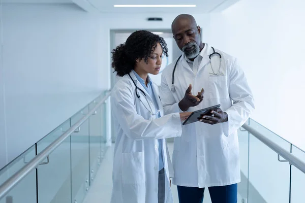 Zróżnicowany Lekarz Mówi Poważnie Patrzy Cyfrową Tabletkę Korytarzu Szpitalnym Usługi — Zdjęcie stockowe