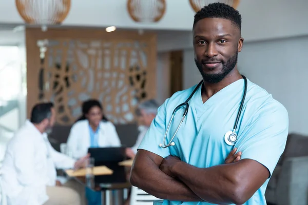アフリカ系アメリカ人男性医師の肖像画 背景で議論の同僚と笑顔 医療サービス — ストック写真