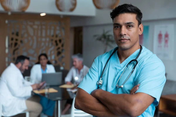 Portrait Mixed Race Male Doctor Arms Crossed Colleagues Discussion Background — Stockfoto