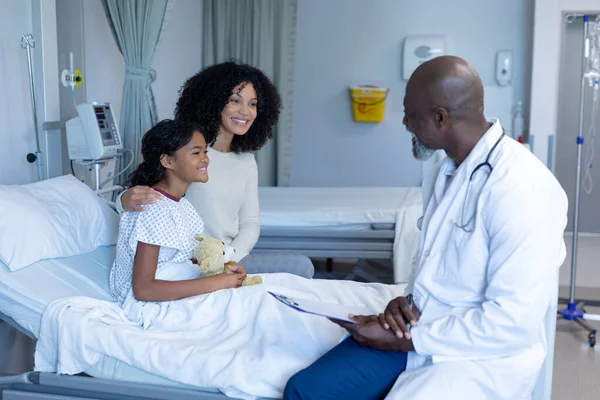 非洲裔美国医生在医院的病床上与混血儿母亲和她生病的女儿交谈 保健和保健服务 — 图库照片
