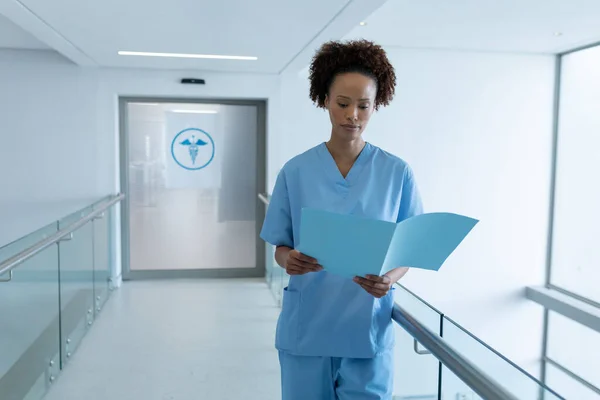 African American Female Doctor Standing Hospital Corridor Looking Medical Documentation — Stock Photo, Image