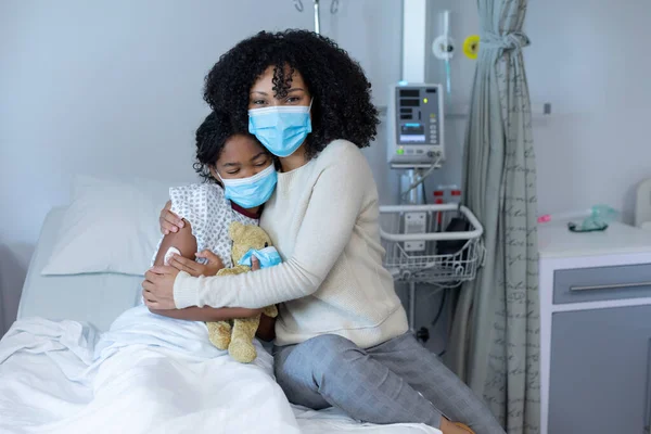 Mixed Race Mother Hugging Sick Daughter Hospital Bed Holding Teddy — Stock Photo, Image