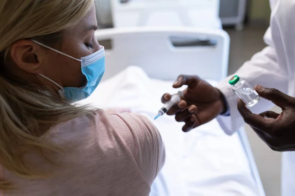 アフリカ系アメリカ人男性医師が入院患者室で白人患者をワクチン接種している コロナウイルスにおける医療 医療サービス Covid 19パンデミック — ストック写真