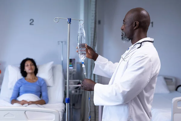 Médico Afro Americano Preparando Saco Gotejamento Para Mulher Mestiça Sentada — Fotografia de Stock