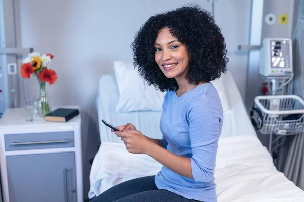 Sorrindo Mestiça Paciente Sexo Feminino Sentado Cama Hospital Usando Smartphone — Fotografia de Stock