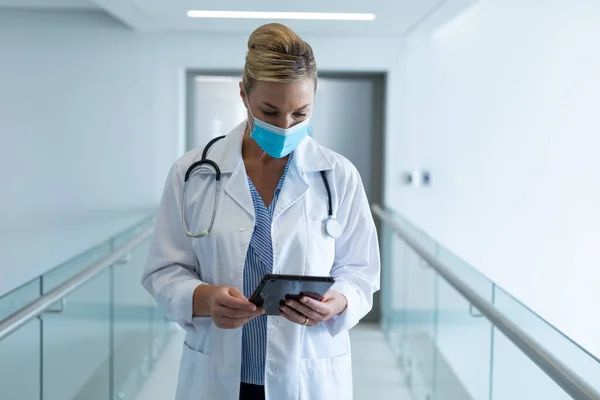 Caucasian Female Doctor Wearing Mask Standing Hospital Corridor Using Tablet — Stock Photo, Image