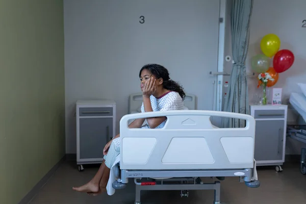 病院のベッドで手に頭を休んで座っている病気の混合レースの女の子退屈 医療サービス — ストック写真