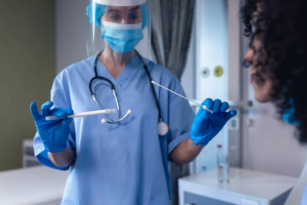 アフリカ系アメリカ人女性の患者はフェイスマスクで女性医師によるスワブ検査を受けた コロナウイルス感染症の治療に従事する医療従事者は — ストック写真