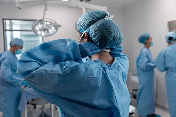 Médico Raça Mista Colocando Máscara Facial Macacões Cirúrgicos Sala Operações — Fotografia de Stock