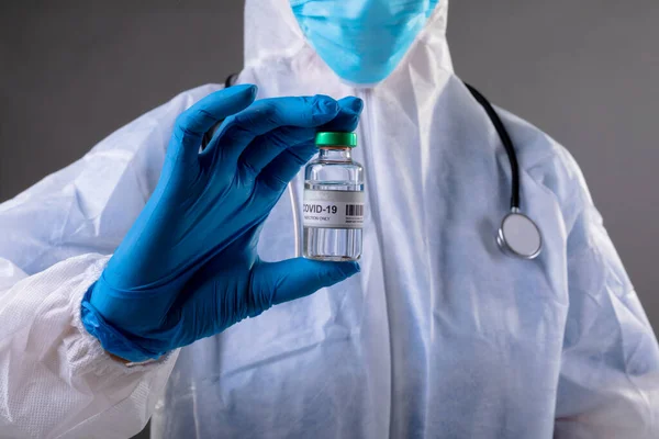 身穿防护服的卫生工作者的中间部分是Covid 19疫苗瓶 预防肠病毒爆发的疫苗注射概念 — 图库照片