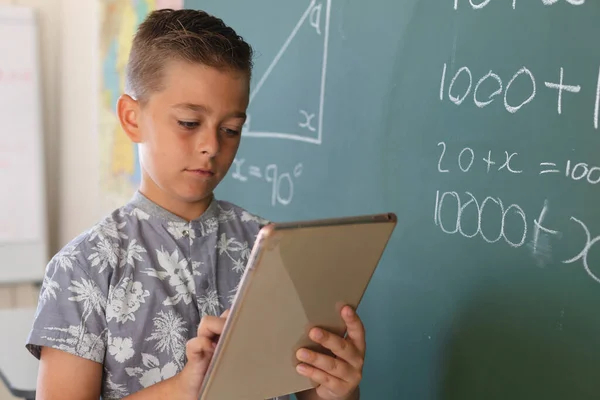 Garoto Caucasiano Quadro Negro Sala Aula Usando Tablet Durante Aula — Fotografia de Stock