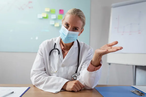 Vit Kvinnlig Läkare Bär Ansiktsmask Sitter Vid Skrivbordet Office Gester — Stockfoto