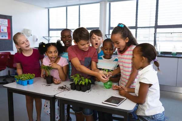 不同类型的学生在学校一起移植和浇灌植物幼苗 学校和教育概念 — 图库照片