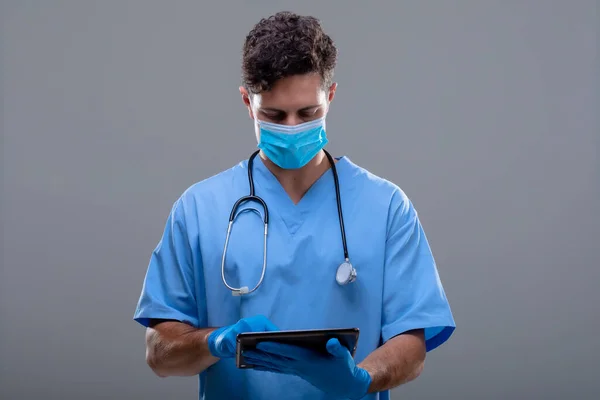 タブレットを使って顔のマスクをした白人男性医師 Covid 19のコロナウイルスパンデミックコンセプト中の医療と医療技術の概念デジタル合成画像 — ストック写真