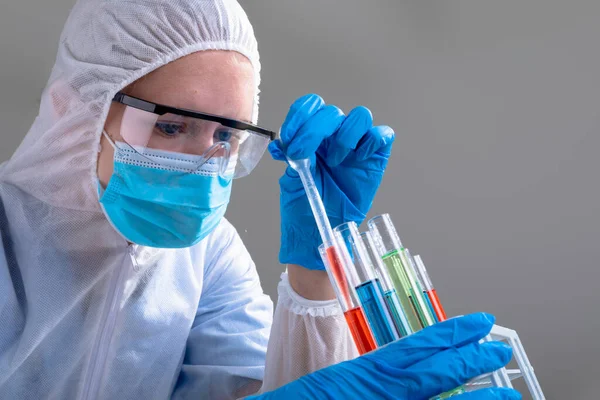 パイプスーツを着た白人女性医師が試験管を持っている Covid 19のコロナウイルスパンデミックの概念の間の医学と医療技術の概念 — ストック写真