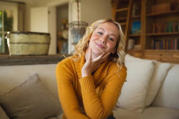 幸せな白人女性の豪華なリビングルームでソファの上に座って 手にもたれ 笑顔の肖像画 家で自由時間を過ごすと — ストック写真