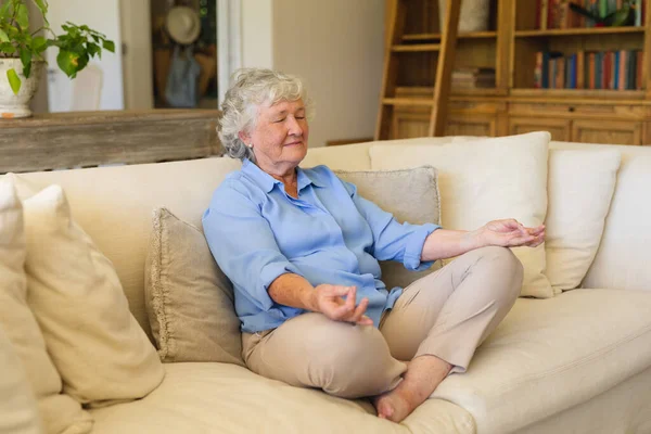 Eine Ältere Kaukasische Frau Sitzt Auf Dem Sofa Und Meditiert — Stockfoto