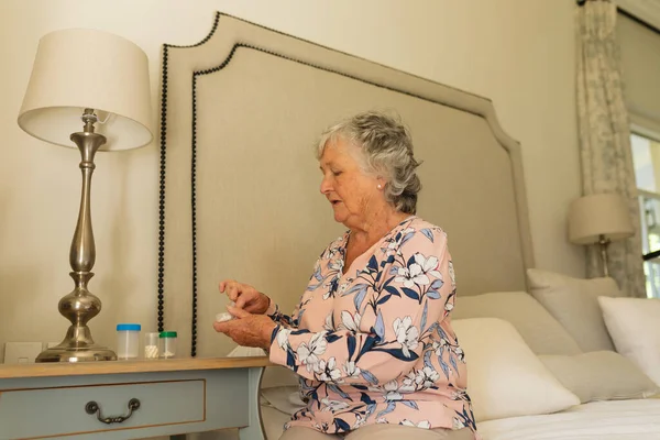 高年级的高加索女人抱着药丸坐在床上 退休和老年生活方式概念 — 图库照片