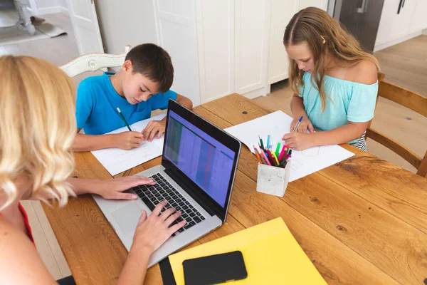白人母亲使用笔记本电脑 女儿和儿子在厨房做作业 家庭家庭生活 在家里一起工作 — 图库照片
