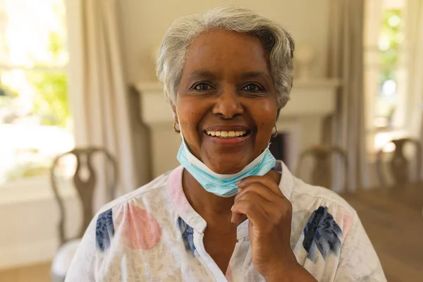 顔のマスクを持つ笑顔シニアアフリカ系アメリカ人女性の肖像画 コヴィド19のパンデミックの概念の下での定年退職と高齢者 — ストック写真