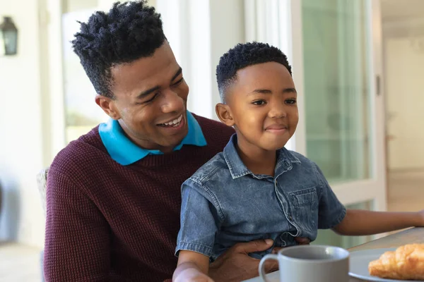 Feliz Hijo Afroamericano Sentado Rodilla Del Padre Mesa Durante Desayuno —  Fotos de Stock