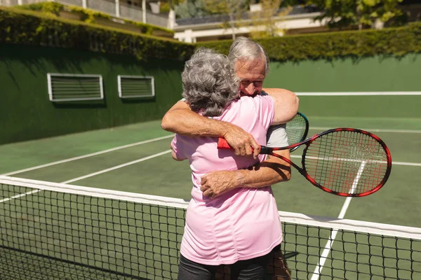 Coppia Caucasica Anziana Che Gioca Tennis Insieme Sul Campo Abbracciando — Foto Stock