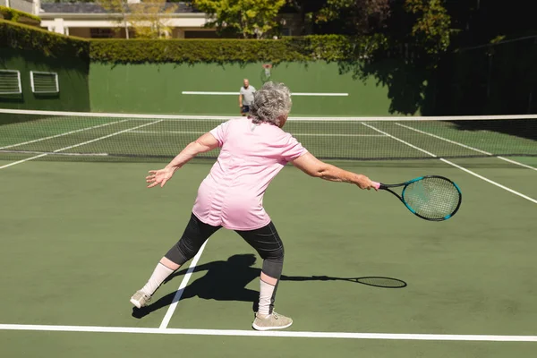 上級の白人夫婦がコートで一緒にテニスをしている 定年退職と積極的なシニアライフスタイルのコンセプト — ストック写真