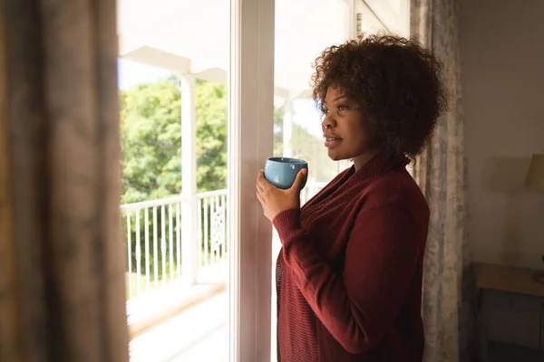 Mujer Afroamericana Feliz Mirando Por Ventana Soleada Sosteniendo Taza Café —  Fotos de Stock