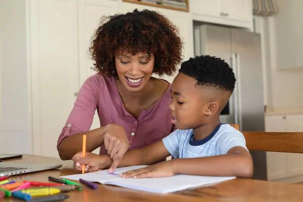 幸せなアフリカ系アメリカ人の母親と息子が笑顔で宿題をしている 家庭内生活を共に学び — ストック写真