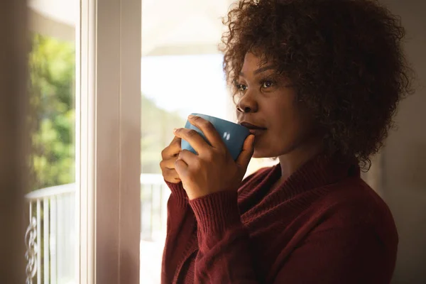 Thoughtful African American Woman Standing Sunny Window Drinking Coffee Smiling — Stock Photo, Image