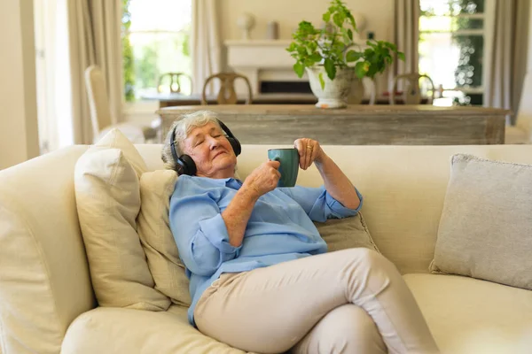 Senior Caucasian Woman Sitting Sofa Wearing Headphones Eyes Closed Retreat — Stock Photo, Image