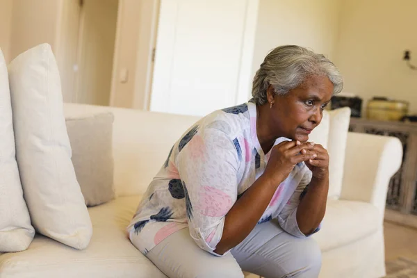 アフリカ系アメリカ人のシニア女性がソファに座って考えます 隠遁と退職とシニアライフスタイルのコンセプト — ストック写真
