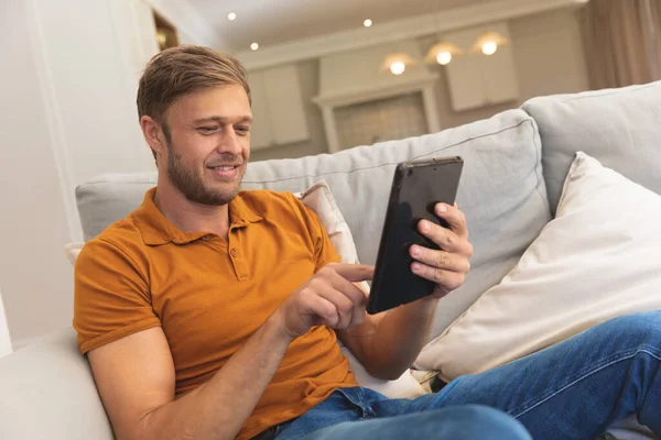 Hombre Caucásico Sentado Sofá Sonriendo Usando Tableta Casa Disfrutando Tiempo — Foto de Stock