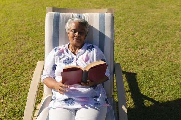 Mujer Afroamericana Mayor Leyendo Libro Tumbona Jardín Soleado Retiro Jubilación — Foto de Stock