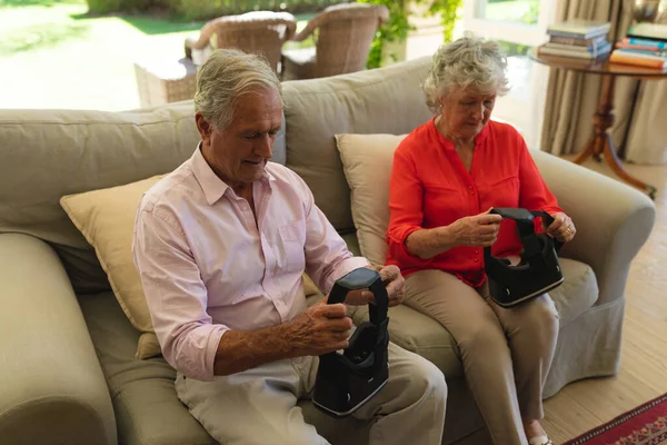 老夫妇坐在沙发上 头戴耳机 坐在客厅里 退休和快乐的老年生活方式概念 — 图库照片