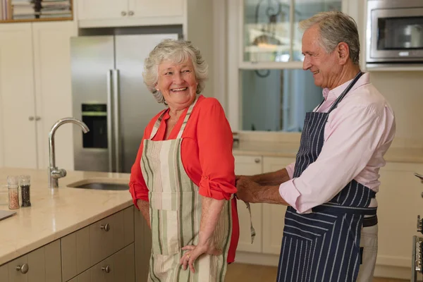 Senior Pareja Caucásica Atando Delantal Sonriendo Cocina Retiro Jubilación Feliz —  Fotos de Stock